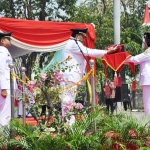 Bupati Sambari menyerahkan bendera merah putih kepada Paskibra untuk dikibarkan. foto: SYUHUD/ BANGSAONLINE