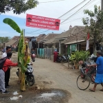Banner yang dipasang warga dan kondisi jalan alternatif Kabupaten Pasuruan-Sidoarjo yang rusak parah di Desa Kedungboto, Kecamatan Beji.