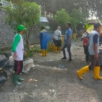 Tim URC DPUTR Gresik dan warga dari Desa Sekarkurung saat bersih-bersih areal parkir peziarah Makam Sunan Giri. Foto: SYUHUD/BANGSAONLINE