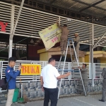 Petugas Satpol PP Bangkalan saat memasang banner teguran terhadap salah satu rumah makan yang diduga tak bayar pajak secara penuh.