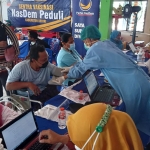 Tenaga Kesehatan dari Dinas Kesehatan Kabupaten Kediri saat melayani peserta vaksinasi yang di gelar oleh Partai Nasdem Kabupaten Kediri di Balai Desa Asmorobangun, Kecamatan Puncu. 