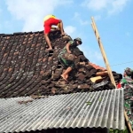 Warga bersama anggota Koramil Kendal bahu membahu memperbaiki atap rumah yang rusak.
