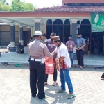 Anggota Satlantas Polres Ngawi sedang membagikan nasi kotak ke para jamaah Salat Jumat.