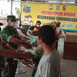 Personel Koramil 0830/05 Tandes saat membagikan paket sembako kepada warga tidak mampu di wilayah Kelurahan Tanjungsari, Kecamatan Sukomanunggal.