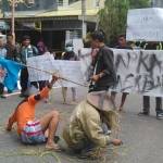 PROTES PEMERINTAH: Aksi teatrikal aktivis PMII Bojonegoro yang digelar di Bundaran Adipura. foto: eki nurhadi/ BANGSAONLINE