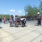 Anggota Forum Biker Tuban (FBT) dibantu anggota Satlantas Polres Tuban sedang membersihkan cor yang tumpah di jalan.