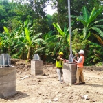 Dua pekerja tampak sedang sibuk memasang besi tower di Desa Sidokerto.