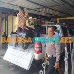 Petugas dari Satlantas Polres Sampang saat mengevakuasi kendaraan roda dua yang terlibat kecelakaan dengan truk muatan besi cor. Foto: MUTAMMIM/BANGSAONLINE 