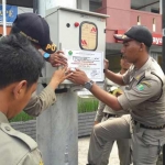 Petugas Satpol PP saat memasang stiker pelanggaran. foto: IWAN IRAWAN/ BANGSAONLINE