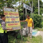 Salah satu petugas Polsek Jetis saat memasang banner imbaukan ke ruas jalan titik rawan kecelakaan, Rabu (14/12/2022).