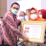 Plt Dirjen PPI, Ismail, menyerahkan penghargaan kepada Wakil Bupati Gresik, Aminatun Habibah. Foto: SYUHUD/ BANGSAONLINE