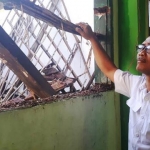 Seorang guru memandangi kondisi  bangunan SMPN 1 Domas Menganti setelah ambruk. foto: ist.