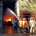 Petugas saat memadamkan api di gudang pengolahan limbah B3, kompleks pergudangan safe n lock, Sidoarjo.