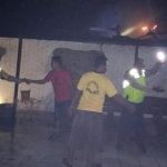 Warga dibantu petugas saat mencoba memadamkan api yang menghanguskan rumah korban.