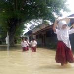 Murid sekolahan SDN Pilang Gede di Kecamatan Balen, mengangkat tasnya agar tak basah. foto: eky nurhadi/ BANGSAONLINE