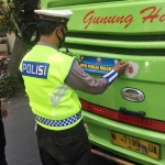 Petugas saat menempelkan stiker di bagian belakang bus Antar Kota Antar Provinsi (AKAP). foto: ist.