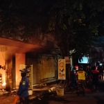 Anggota Polsek Bangil dibantu Anggota Koramil Bangil saat memadamkan kebakaran toko kelontong di Jalan Raya Diponegoro, Bangil.