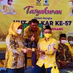 dr. Anis Ambiyo Putri menerima potongan tumpeng dari Ketua Golkar Gresik Anha usai resmi bergabung di Golkar Gresik. foto: SYUHUD/ BANGSAONLINE