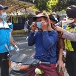 Petugas dari Polsek Ngadiluwuh dan relawan saat membagikan dan memasangkan masker kepada pengguna jalan. (foto: ist).