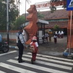 Petugas Dishub saat menyebrangkan anak sekolah.
