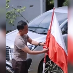 Ketua Komisi I DPRD Pasuruan Sugiarto saat membetulkan bendera merah putih di jalan yang pemasangannya terbalik.