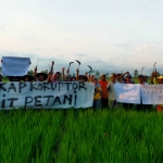 Puluhan petani di Lumajang, membentangkan spanduk desak KPK usut dugaan korupsi di Kementan. 