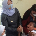 Wali Kota Mojokerto, Ika Puspitasari, berupaya menenangkan salah satu siswi yang ketakutan saat disuntik vaksin.