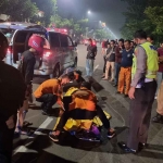 Petugas saat mengevakuasi pemotor yang tewas usai tabrak truk di Jalan Manyar Kertoarjo, Surabaya.