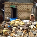 Mbah Yem membendung rumahnya dari terjangan ombak dengan batu dan sak berisi pasir.