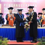 Gubernur Jawa Timur Dr. H. Soekarwo, SH.MM, mendapat ucapan selamat dari Rektor UMM Dr. H. Fauzan, M.Pd, usai menerima gelar Doktor Honoris Causa (HC). 