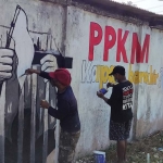 Wiwied Asri Sutanto saat melukis bendera putih dan mural lain dibantu rekannya, Musim. foto: MUJI HARJITA/ BANGSAONLINE