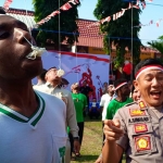 Kapolres Blitar AKBP Adewira Negara Siregar (kanan) kalah cepat dengan pelajar asal Papua saat lomba makan kerupuk.