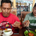 Mesakh Kusdianto dan Sutrisno, pengunjung Kedai Gogo Iwak Kali saat menikmati menu masakan sop kutuk dan rica-rica kutuk. foto: MUJI HARJITA/ BANGSAONLINE