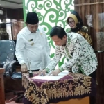 TEKEN: Dekan FE Unesa Eko Wahjudi menandatangani MoU Sekolah Pasar disaksikan Bupati H Saiful Ilah dan Kadisperindag Fenny Apridawati, Kamis (27/12). foto: MUSTAIN/ BANGSAONLINE