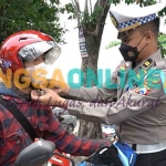 Kanit Regident, Iptu Mega Satriatama membagikan helm SNI kepada pengguna jalan. Foto: SYUHUD/BANGSAONLINE.com