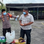 Kapolsek Gedangan Kompol Heri Siswoko membagikan masker kepada warga di Masjid Al Maruf Desa Bangah, Kecamatan Gedangan, Kabupaten Sidoarjo, Jumat (26/2/2021). (foto: ist)