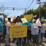 Massa aksi saat menunjukkan poster kritikan di depan pintu Kejari Sampang. Foto: MUTAMMIM/BANGSAONLINE
