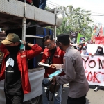 Personel Polresta Sidoarjo saat memberi masker kepada mahasiswa yang sedang menggelar demo.