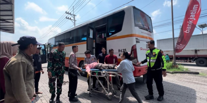 Petugas saat mengevakuasi seorang pemudik yang pingsan dari Bus Harapan Jaya rute Jombang-Mojokerto