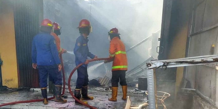 Petugas usai menjinakkan api yang melalap toko cat dan tiner di Sidoarjo.