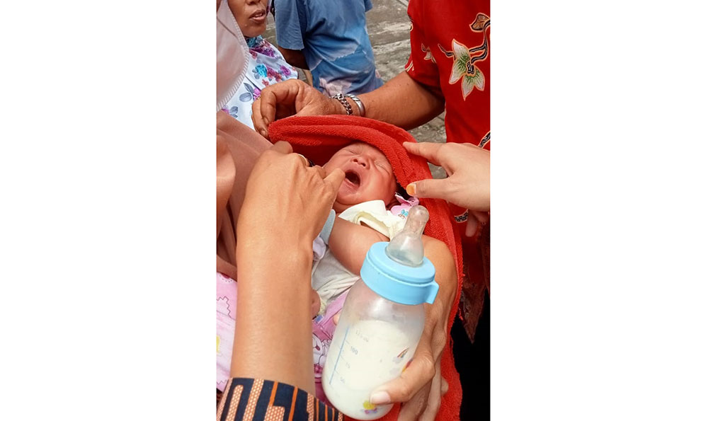 Seorang wanita saat menggendong bayi perempuan yang dibuang orang tuanya di depan rumah warga Balongbendo, Sidoarjo.