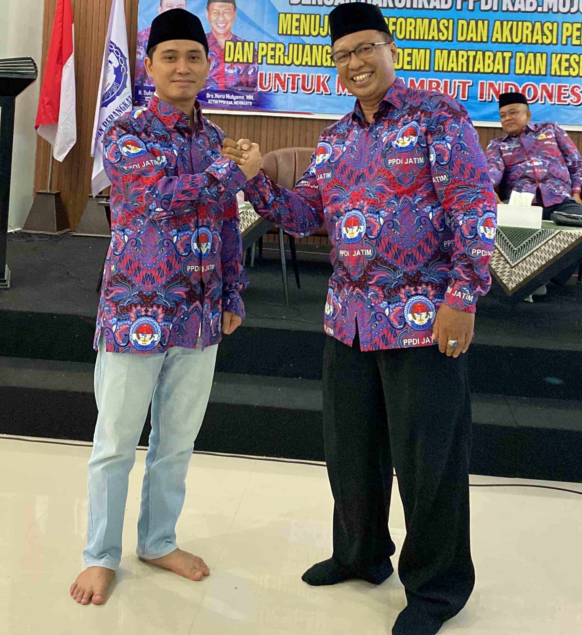 Ketua PPDI Mojokerto Heru Mulyana berjabat tangan dengan Gus Barra setelah mengenakan baju seragam PPDI kepada calon bupati Mojokerto 2004 itu. Foto: bangsaonnline