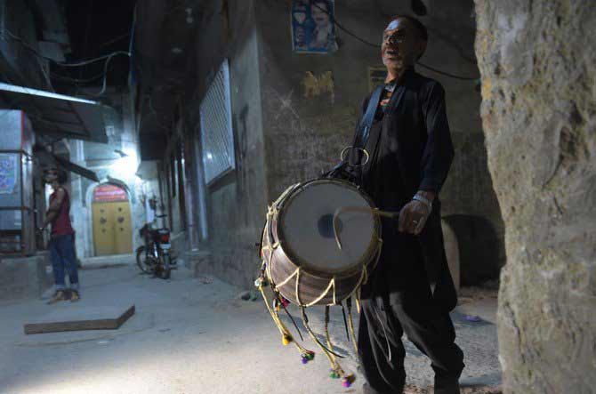 Gambar ini diambil pada 30 Mei 2018. Tampak seorang pria Pakistan Lal Hussain (C), 66, tengah menabuh drumnya untuk membangunkan warga agar makan sahur di Bani, daerah pemukiman tua, di Rawalpindi. (AFP) 