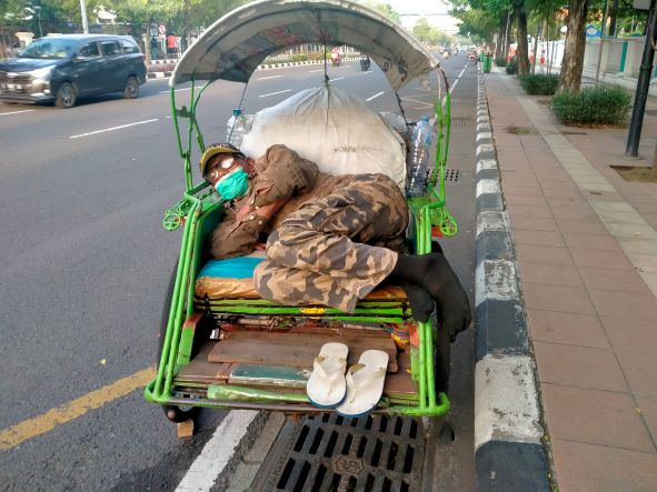 Tukang becak ini tidur nyenyak di atas becaknya. Foto ini diambil di Jl Prof Dr Moetopo Kota Surabaya, Kamis (7/4/2022). Foto: mma/bangsaonline.com