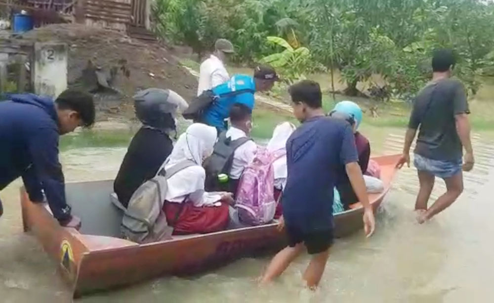Warga di Kecamatan Balongpanggang saat mengantarkan siswa SD berangkat sekolah dengan perahu dampak desa terendam luapan Kali Lamong. foto: SYUHUD/ BANGSAONLINE