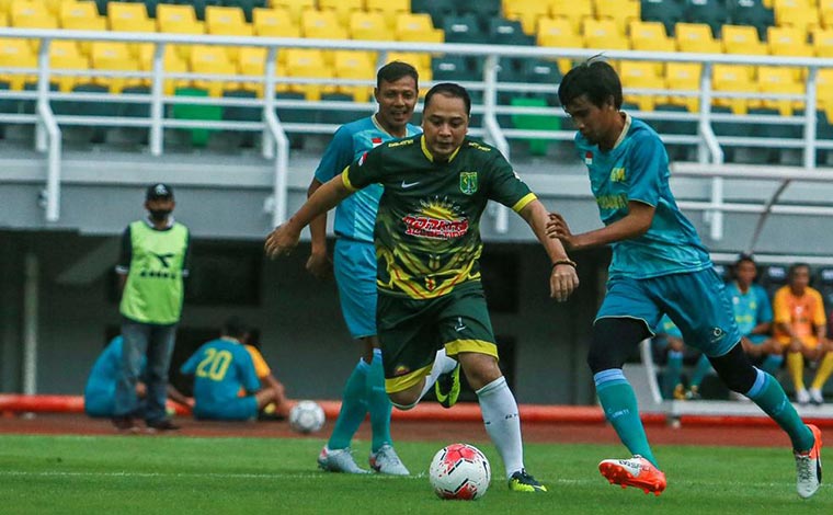 Wali Kota Surabaya Eri Cahyadi saat menggiring bola dikawal pemain Sidoarjo All Star dalam pertandingan uji coba lapangan Stadion GBT, Sabtu (13/3/21).