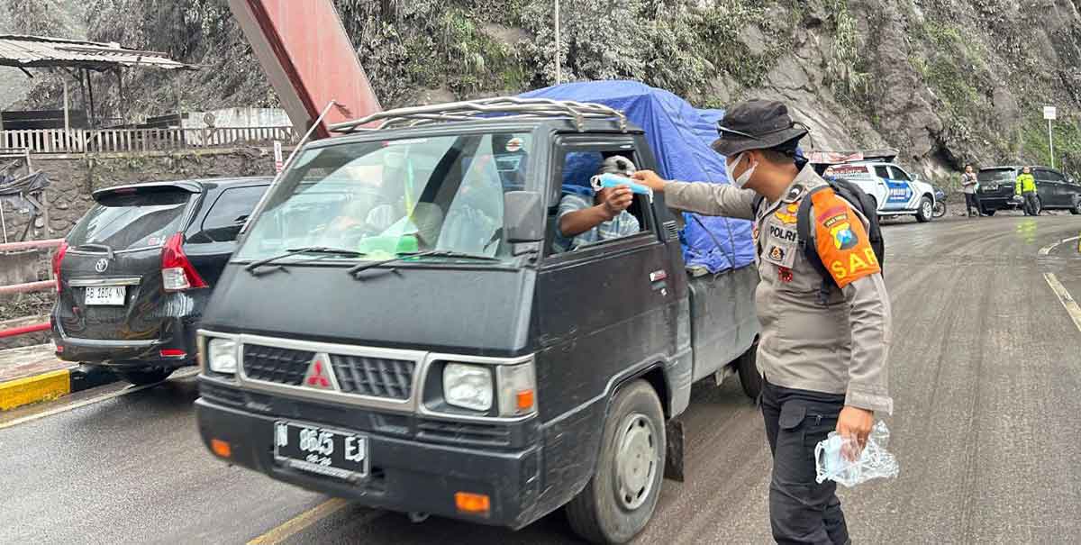 Petugas dari Tim SAR Polda Jatim saat membagikan masker ke salah satu pengendara di Jembatan Gladak Perak, Lumajang.