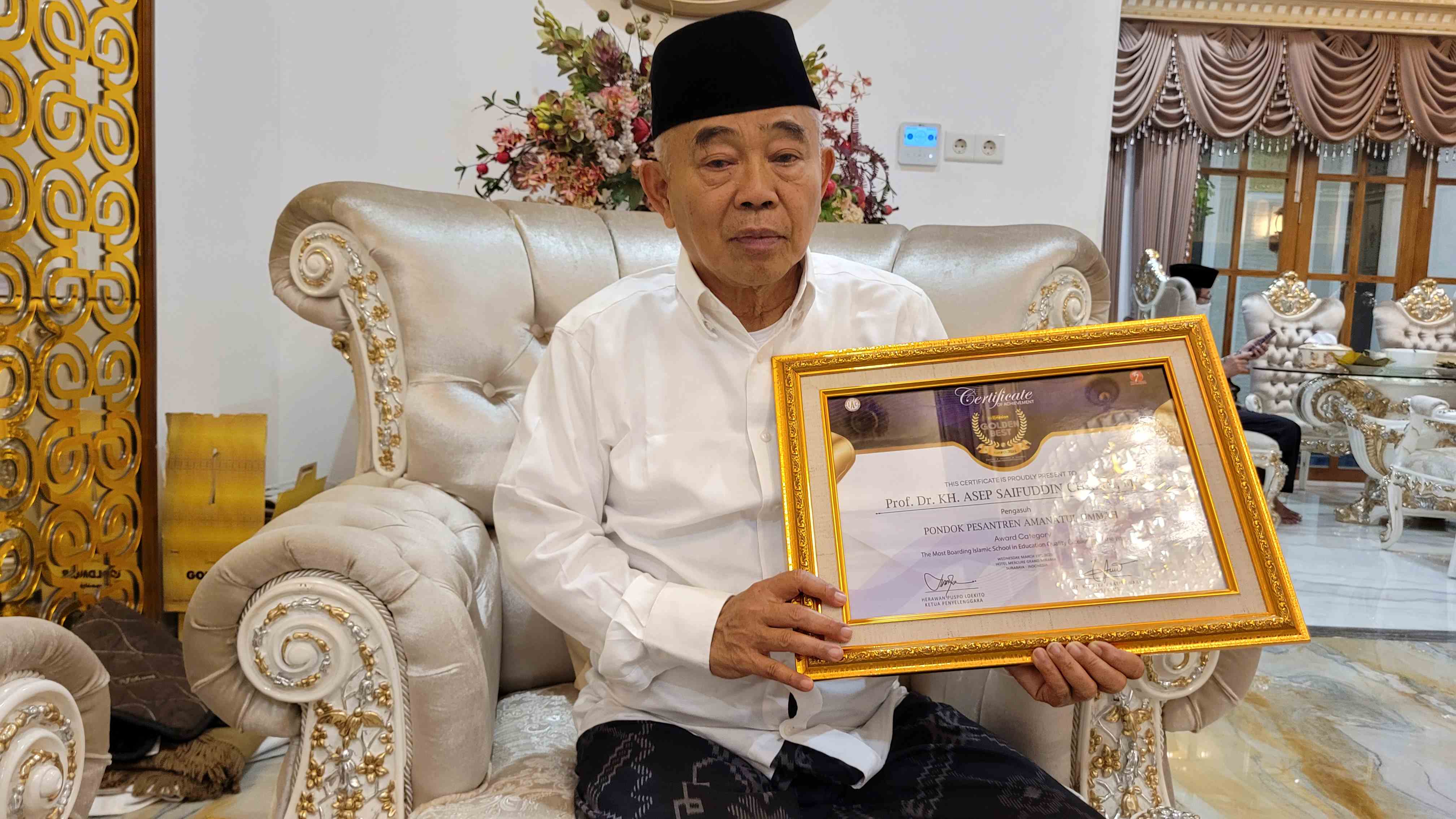 Prof Dr KH Asep Saifuddin Chalim, MA, memegang sertifikat penghargaan The Most Boarding Islamic School in Education Quality Exellence of the Year di kediamannya di Jalan Siwalankerto Utara Surabaya, Jumat (21/3/2025). Foto: MMA/bangsaonline