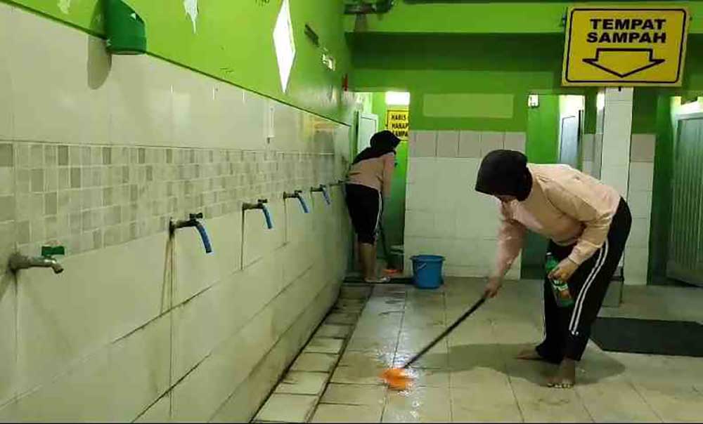 Tampak dua polwan sedang membersihkan toilet dan area tempat wudlu masjid.