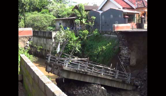 Jembatan yang putus akibat derasnya arus sungai. foto : arif kurniawan/ BANGSAONLINE